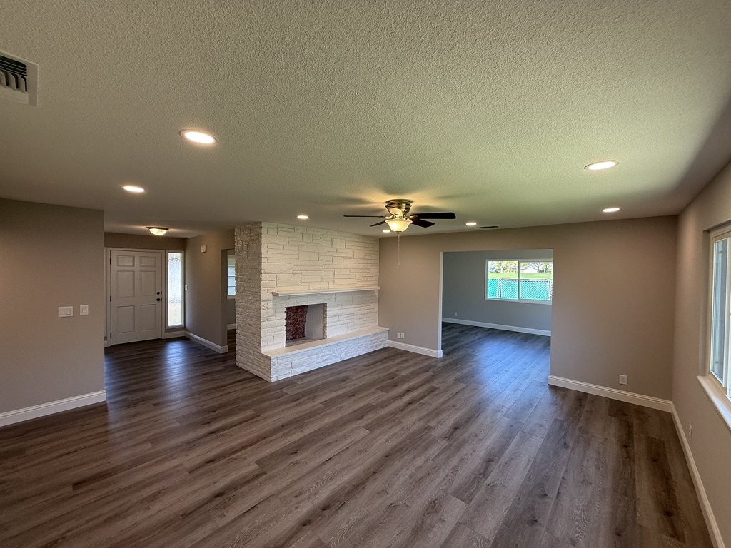 The Woodworth Avenue living room after renovation, with a refinished stone fireplace and new flooring